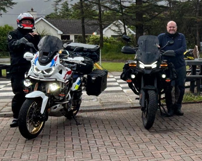 Two Future Eyes Ireland riders with their adventure bikes — a Honda Africa Twin and Triumph Tiger fitted with Future Eyes auxiliary lights